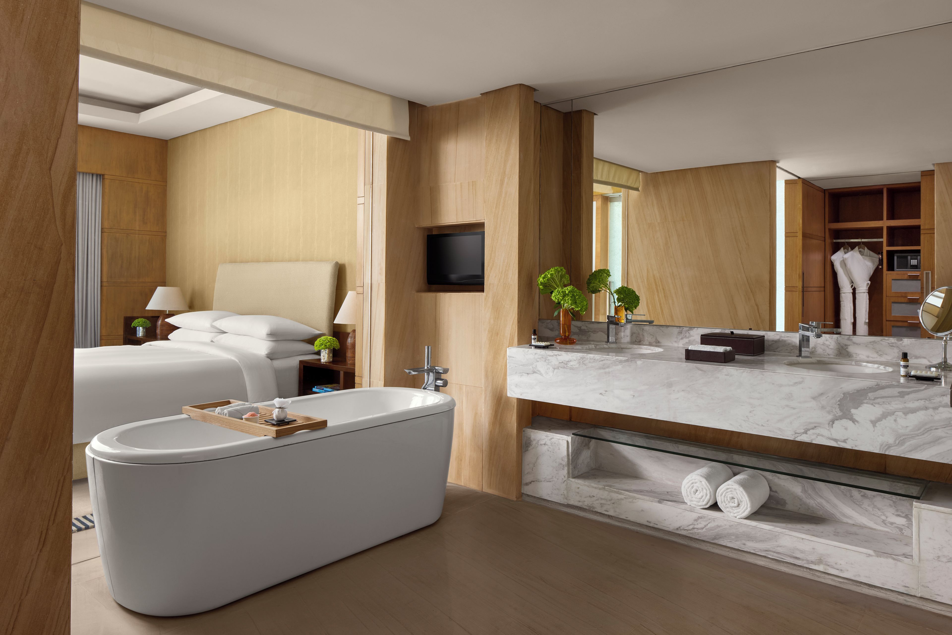 A modern bathroom with a freestanding bathtub, a large mirror, and a marble countertop.