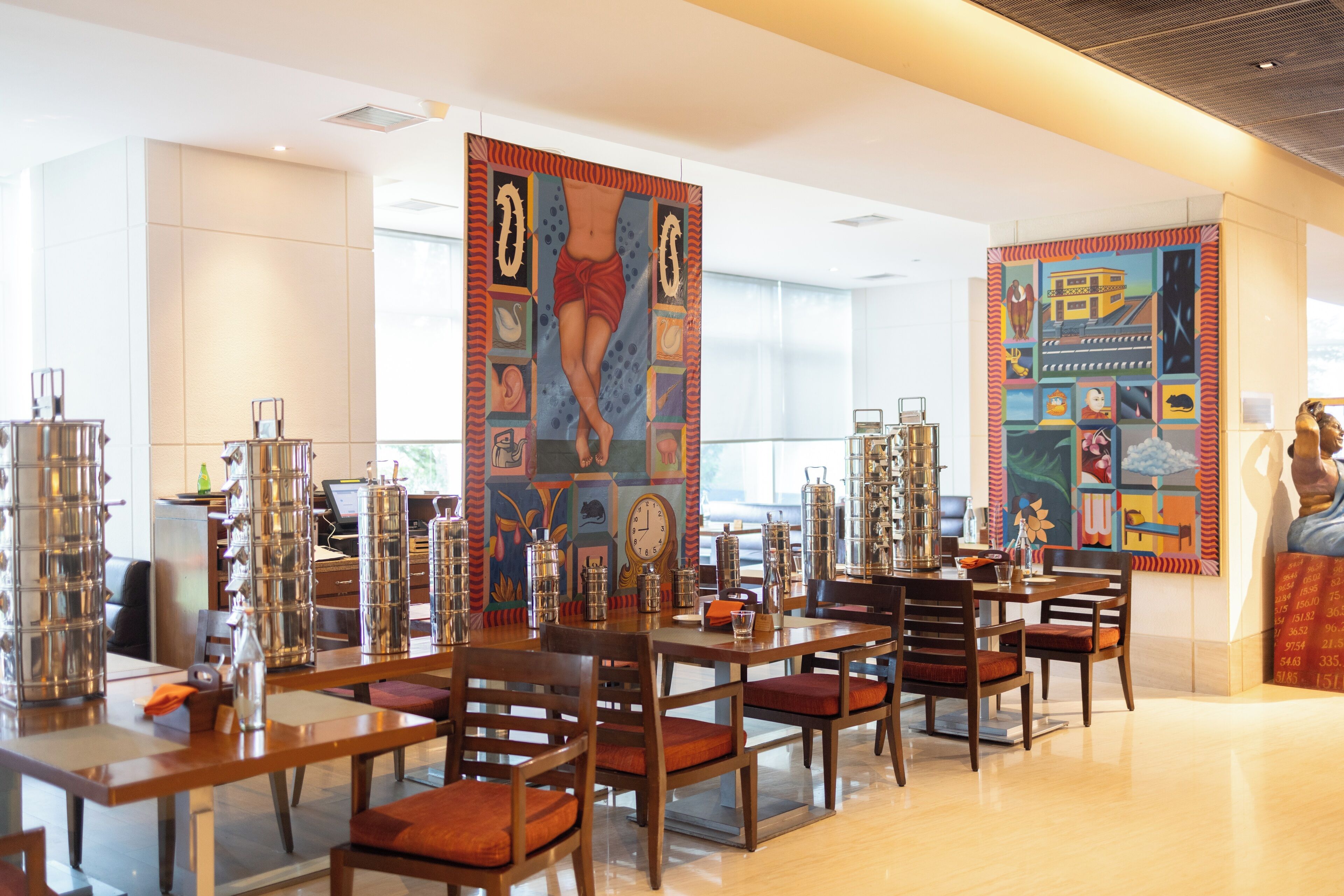 A modern hotel lobby with a spacious seating area, large artwork on the walls, and a variety of decorative items on the tables.
