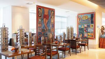 A modern hotel lobby with a spacious seating area, large artwork on the walls, and a variety of decorative items on the tables.