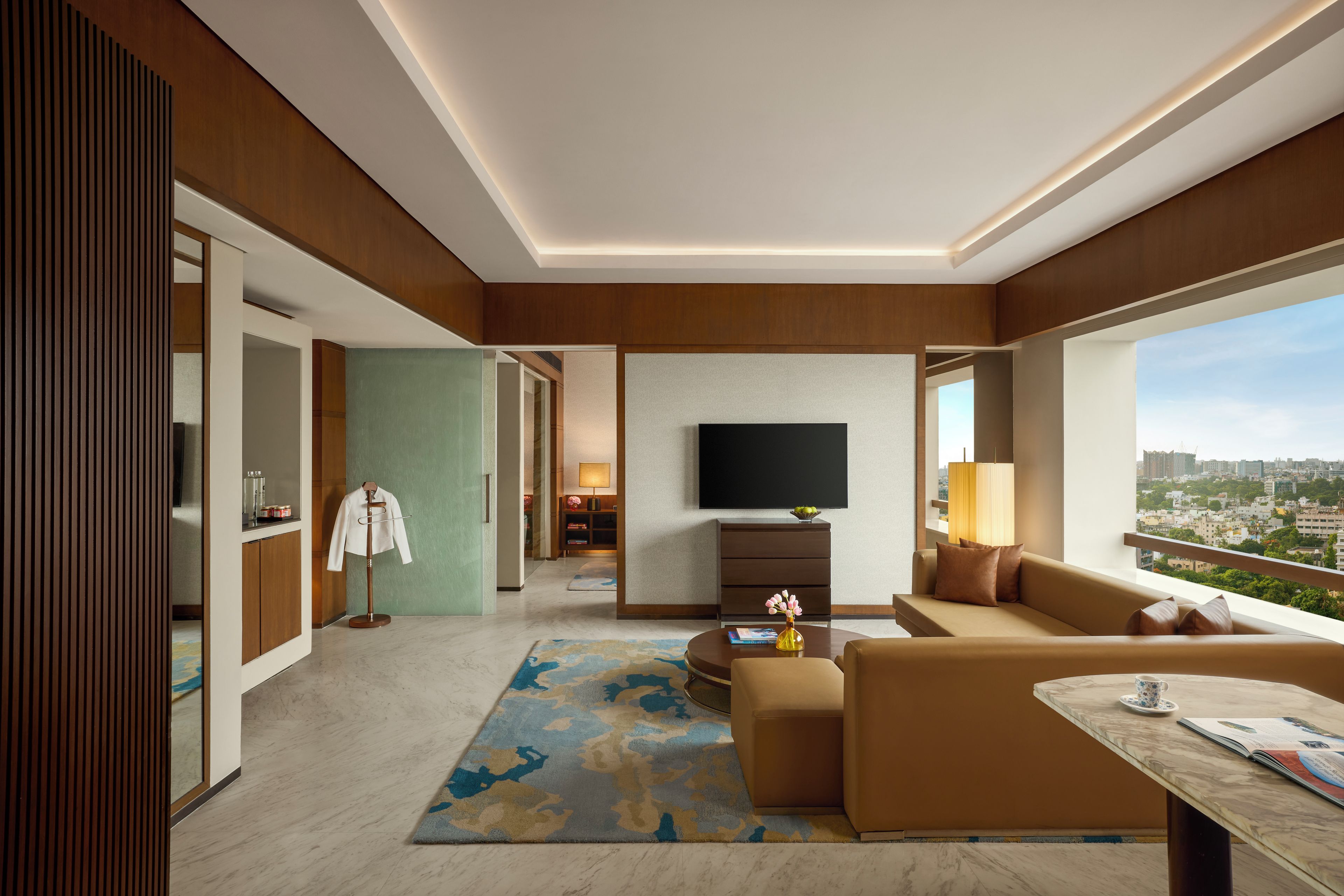 Een moderne hotelkamer met een flatscreen-tv, een bank, een salontafel en uitzicht op de stad.