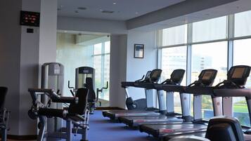 A gym with treadmills, weight machines, and a digital clock displaying the time.