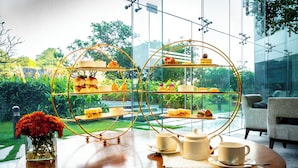 A dining table with a glass display case containing pastries and a vase of flowers. - Hyatt Regency Chennai (Chennai)