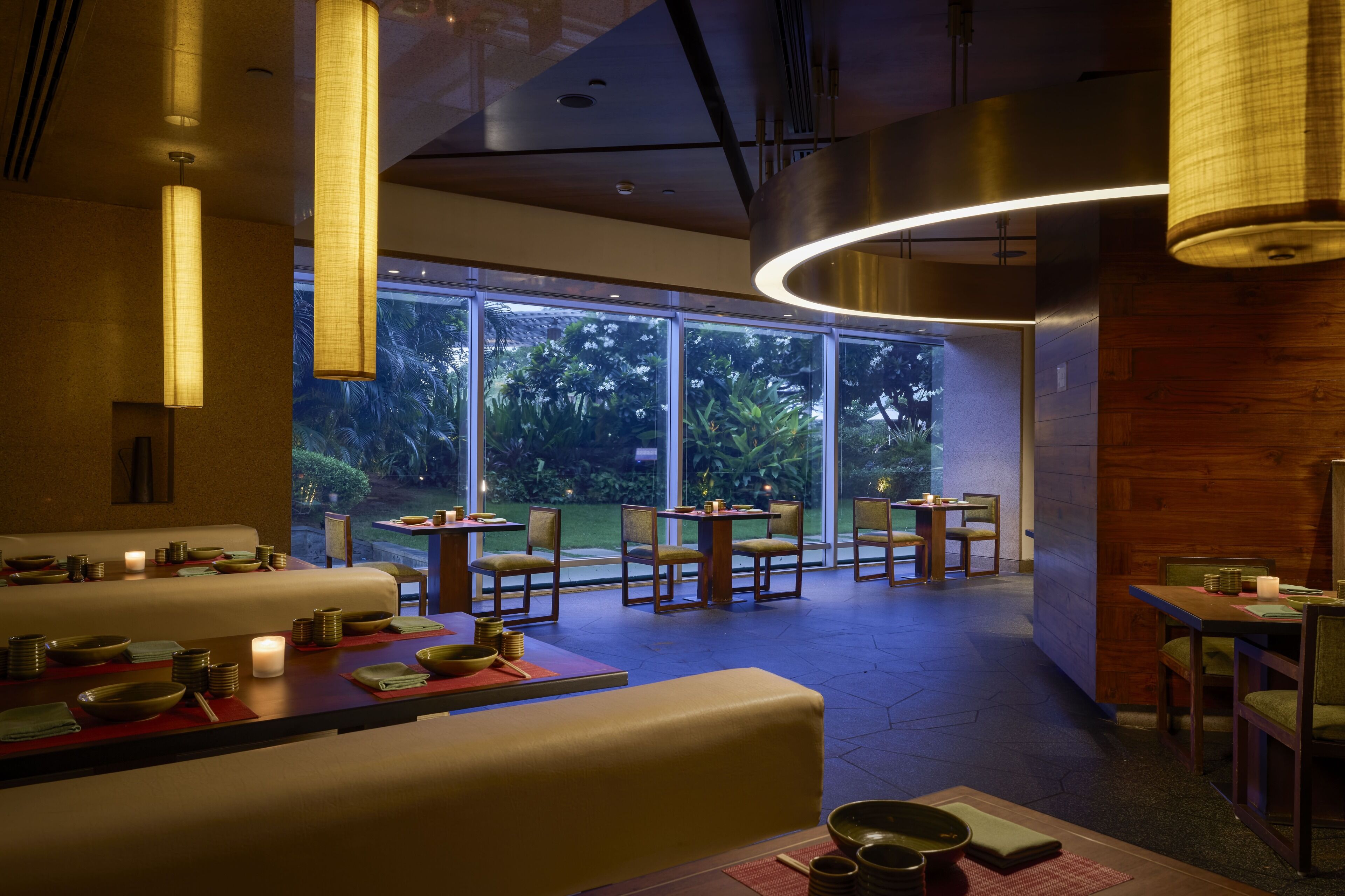 Ein Restaurant mit modernem Interieur, großen Fenstern und Blick auf Grünflächen.