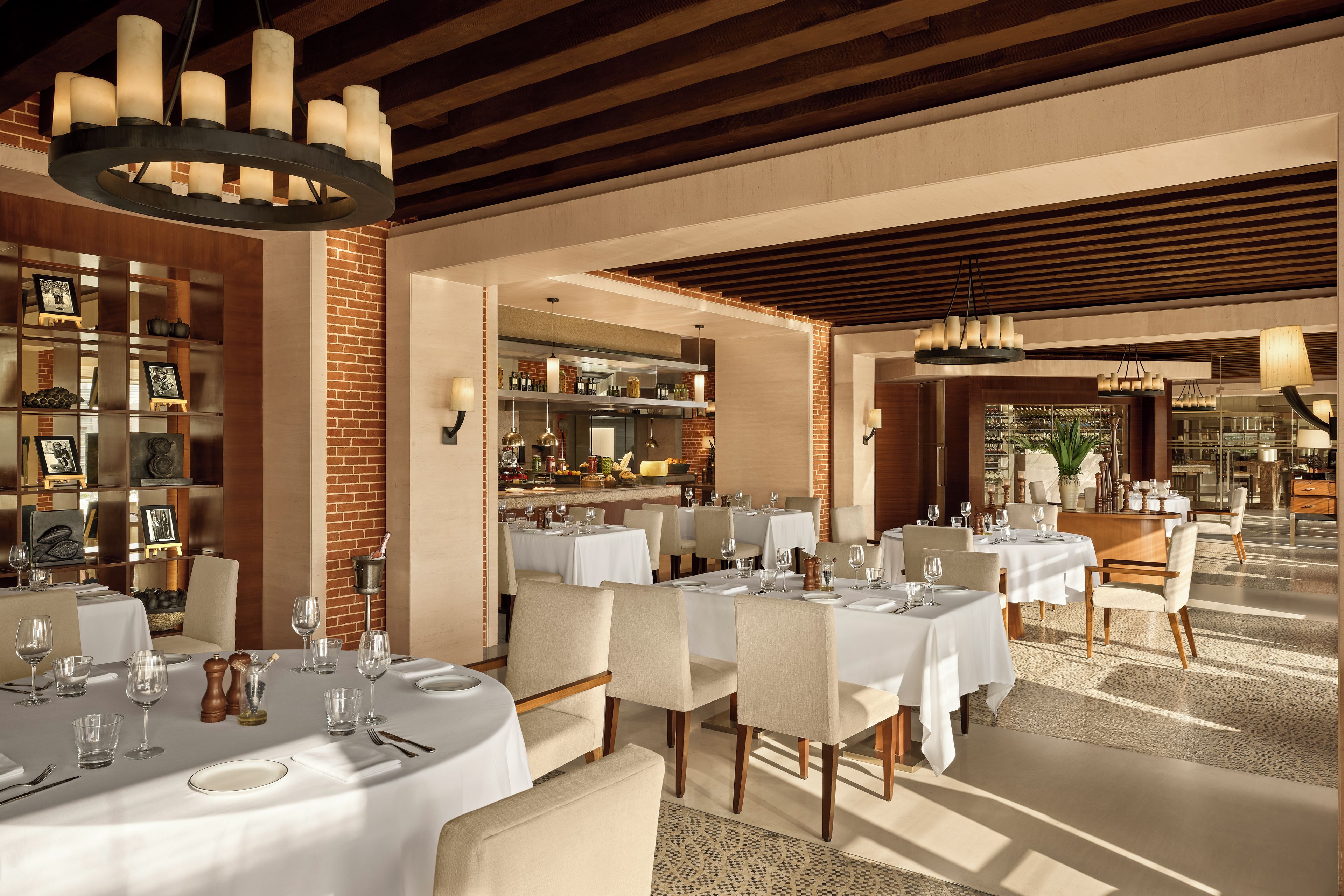 Un restaurante con mesas redondas, manteles blancos y una pared de ladrillo.