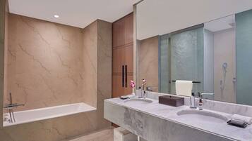 A modern bathroom with a marble vanity, a bathtub, and a large mirror.