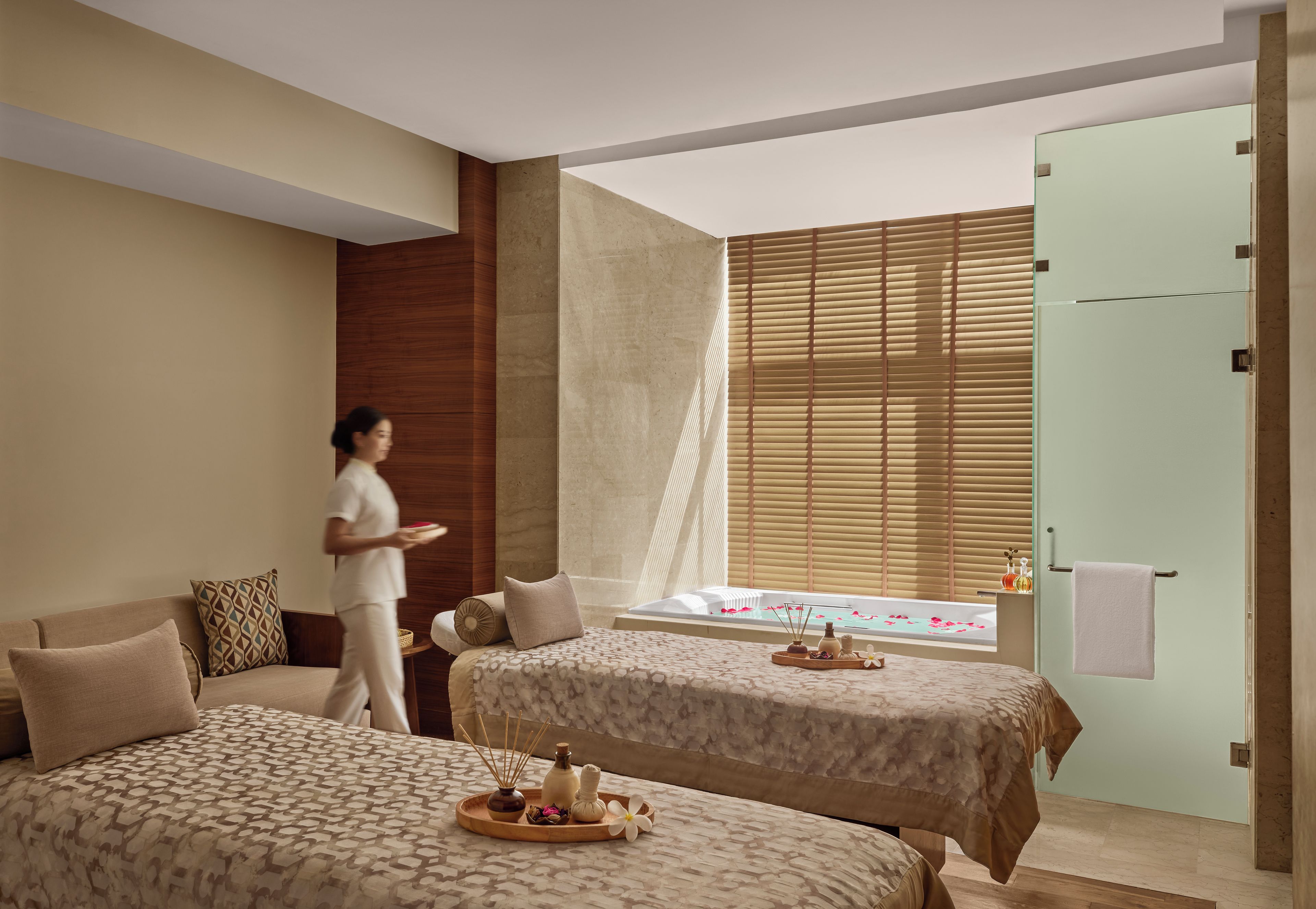 Habitación de hotel con dos camas, una ventana con persianas, una bañera y un perchero para toallas.