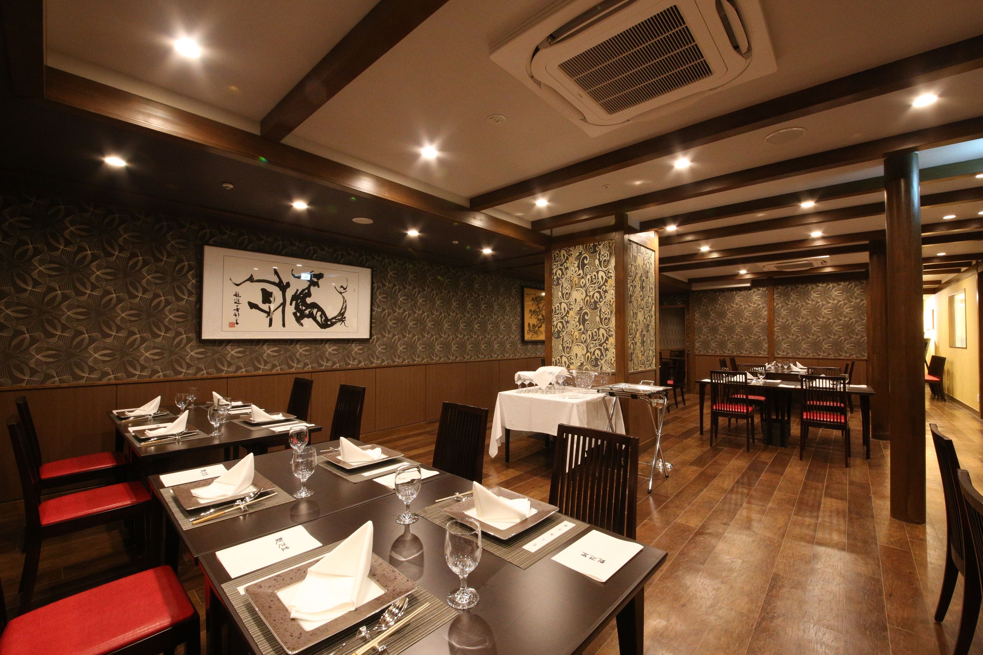 Un espace repas avec des tables disposées pour accueillir quatre personnes, des chaises et un mur décoratif agrémenté d’une œuvre d’art encadrée.