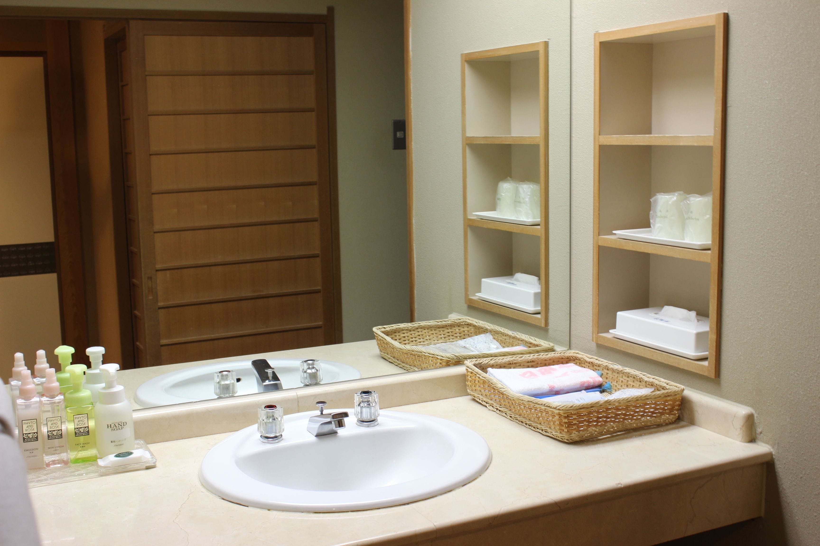 A bathroom with two sinks, a mirror, and shelves with toiletries.