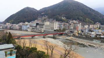 A cityscape with a red bridge over a river, surrounded by buildings and a mountain.