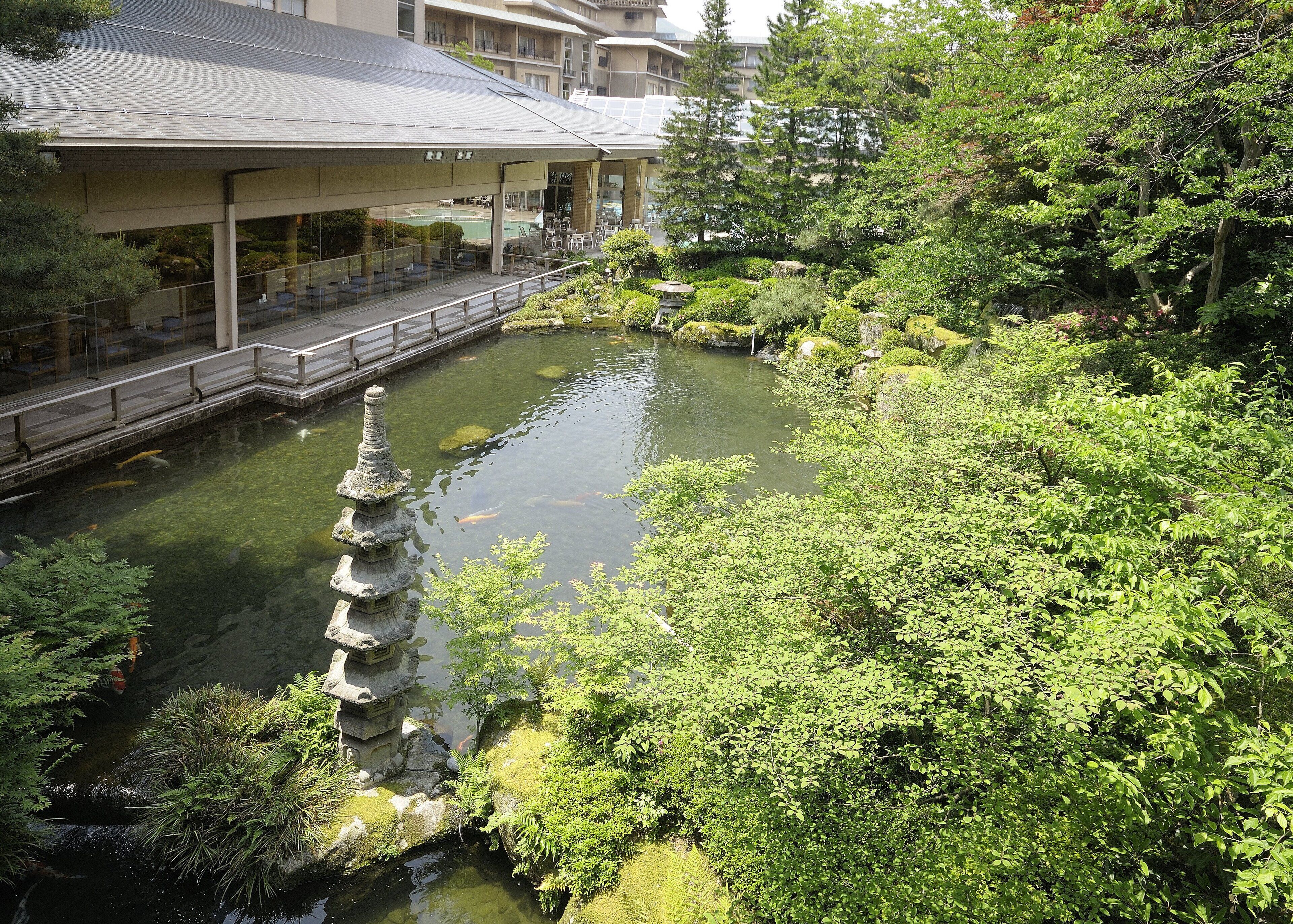 A traditional Japanese garden with a koi pond, stone lantern, and lush greenery.