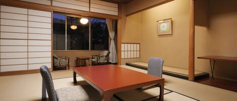 Una habitación japonesa tradicional con suelo de tatami, una baja mesa de madera y un sofá de tatami.