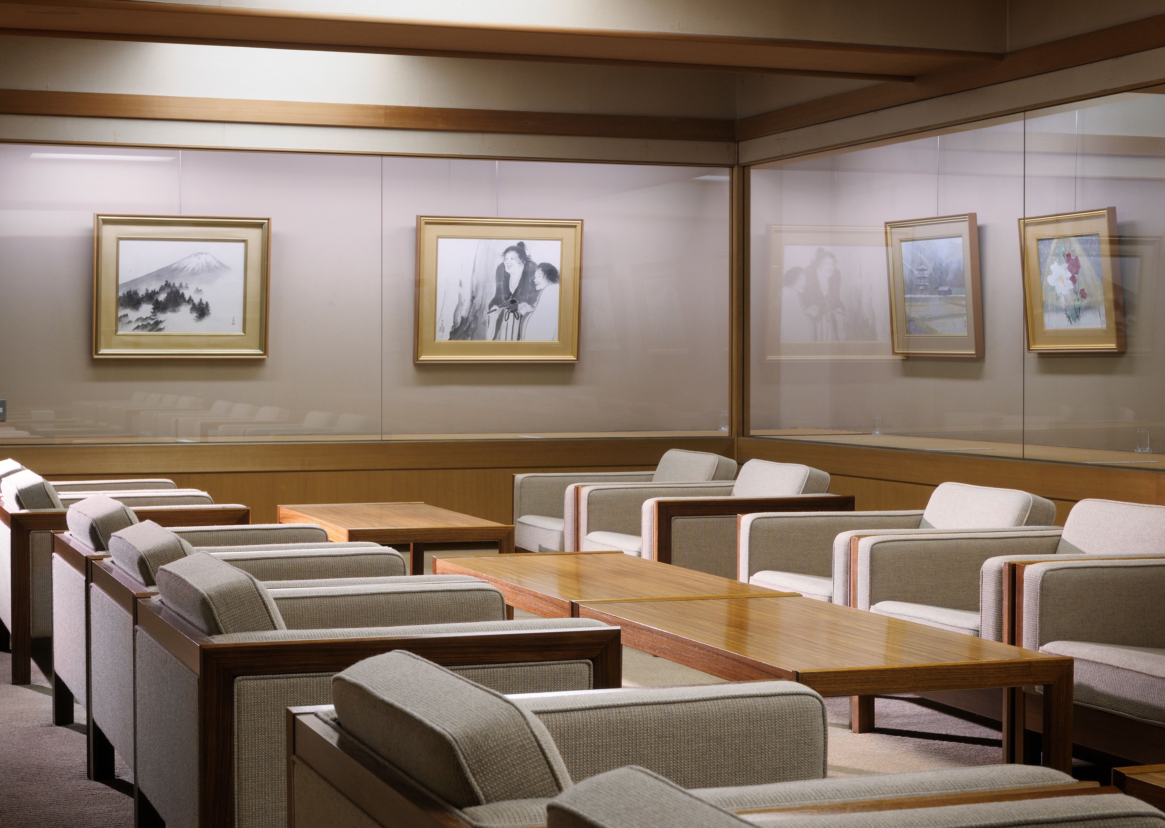 Une salle de conférence avec des rangées de chaises, une longue table et des œuvres d’art encadrées accrochées aux murs.