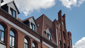 Un bâtiment historique en briques, doté de fenêtres en arc de cercle et d’une tour imposante.