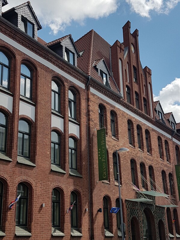 Un edificio histórico de ladrillo con ventanas de arco y una torre destacada.