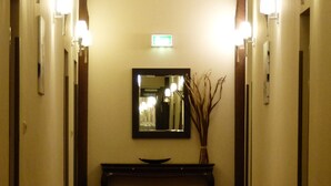 Un couloir doté d’un plafond en arc de cercle, d’un miroir fixé au mur et d’une console sur laquelle est posé un vase.