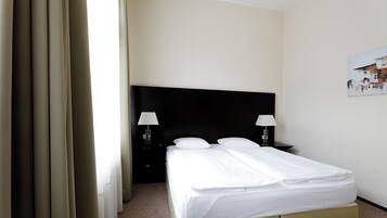 A hotel room with a bed, two bedside tables with lamps, a headboard, and a painting on the wall.