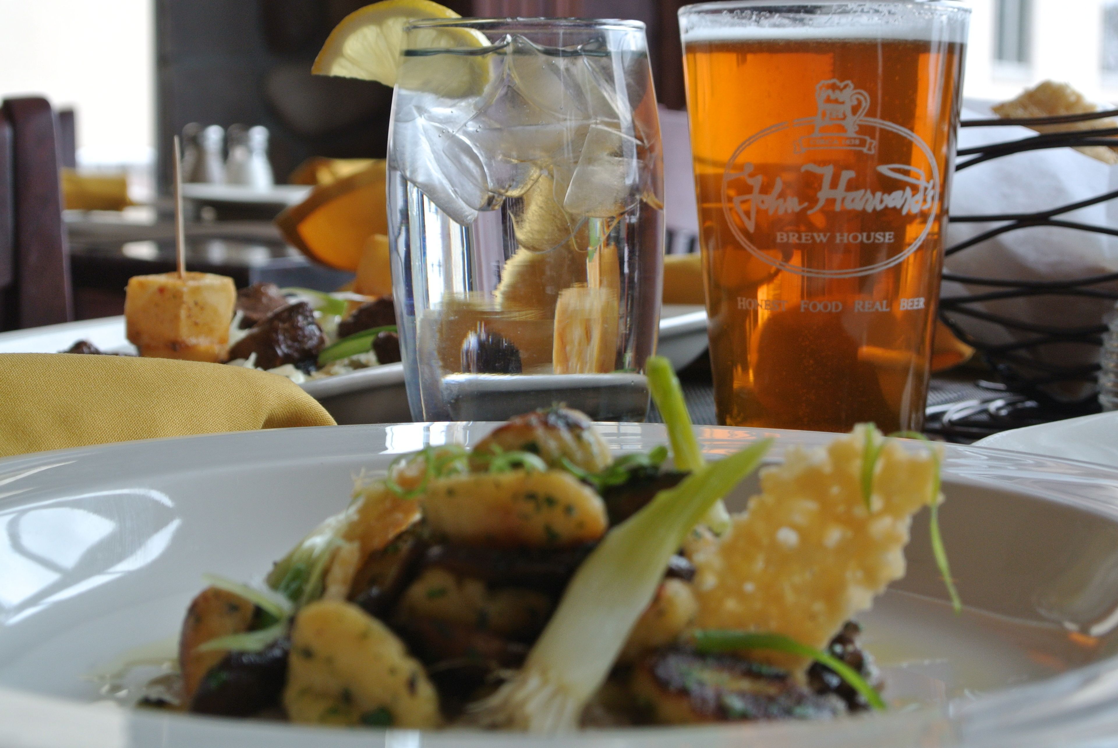 A dining table with a plate of food, a glass of beer, and a menu.