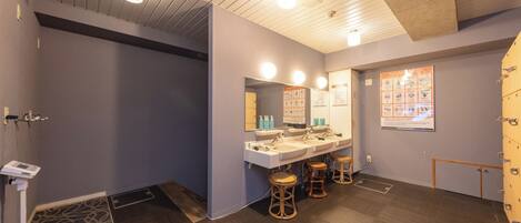 Un baño moderno con un espejo grande, tres lavamanos y un mueble de tocador de madera.