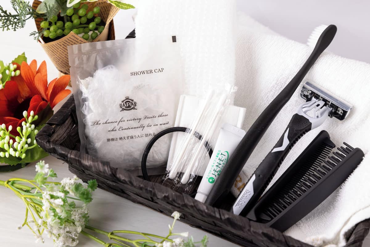 A bathroom vanity with a white towel, a black comb, a white bottle, and a black razor.