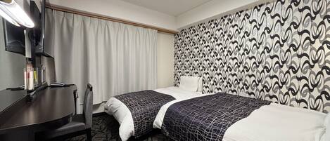 Ett hotellrum med två sängar, ett skrivbord, en stol, en TV och tapeter med ett mönster.