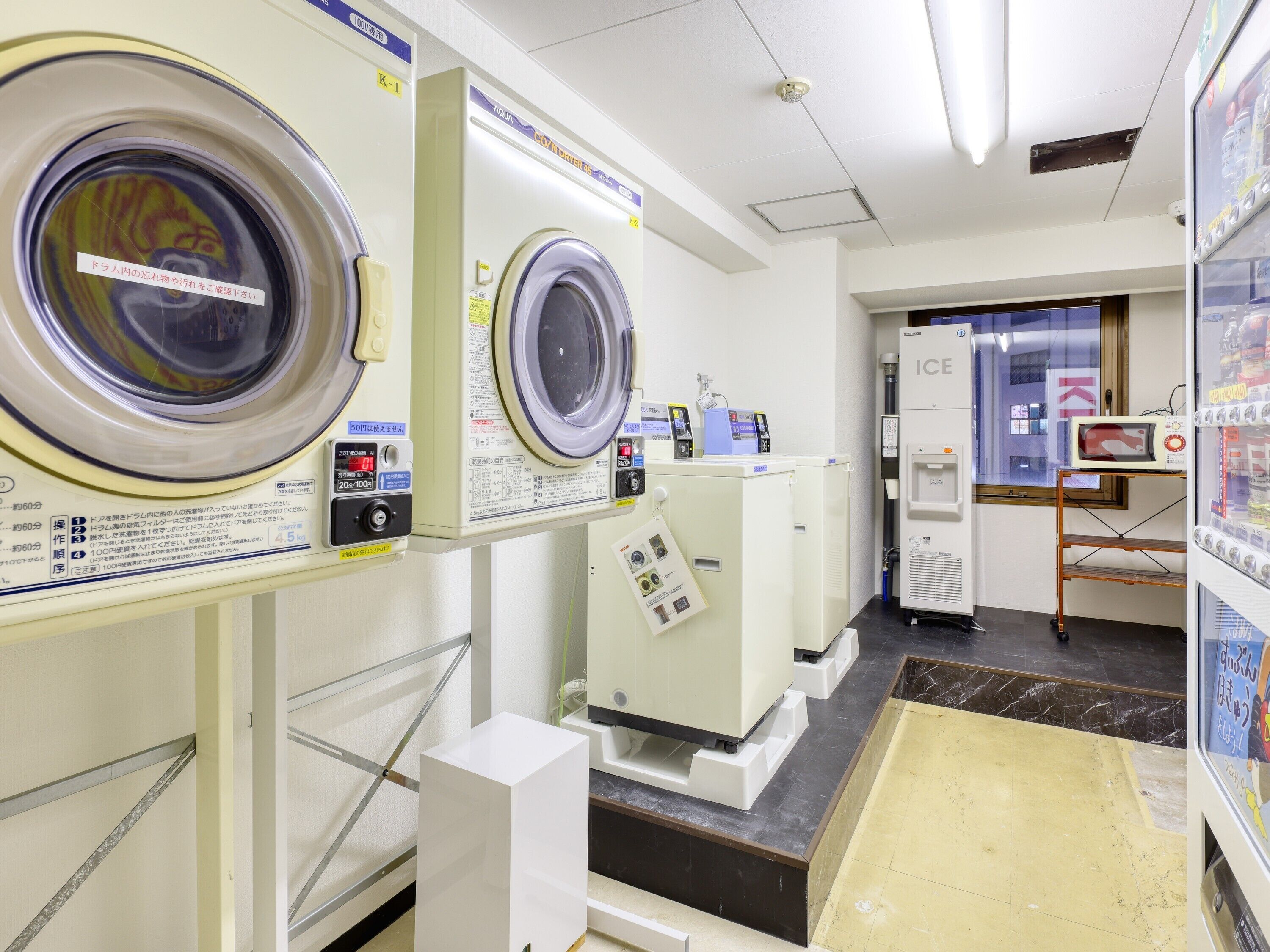 A laundry facility with multiple washing machines, a water dispenser, and a microwave.