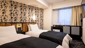 Habitación de hotel con dos camas, un escritorio, una silla, un televisor y una ventana con cortinas.