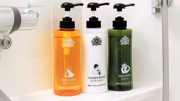 Three bottles of body soap, conditioner, and shampoo on a bathroom shelf.