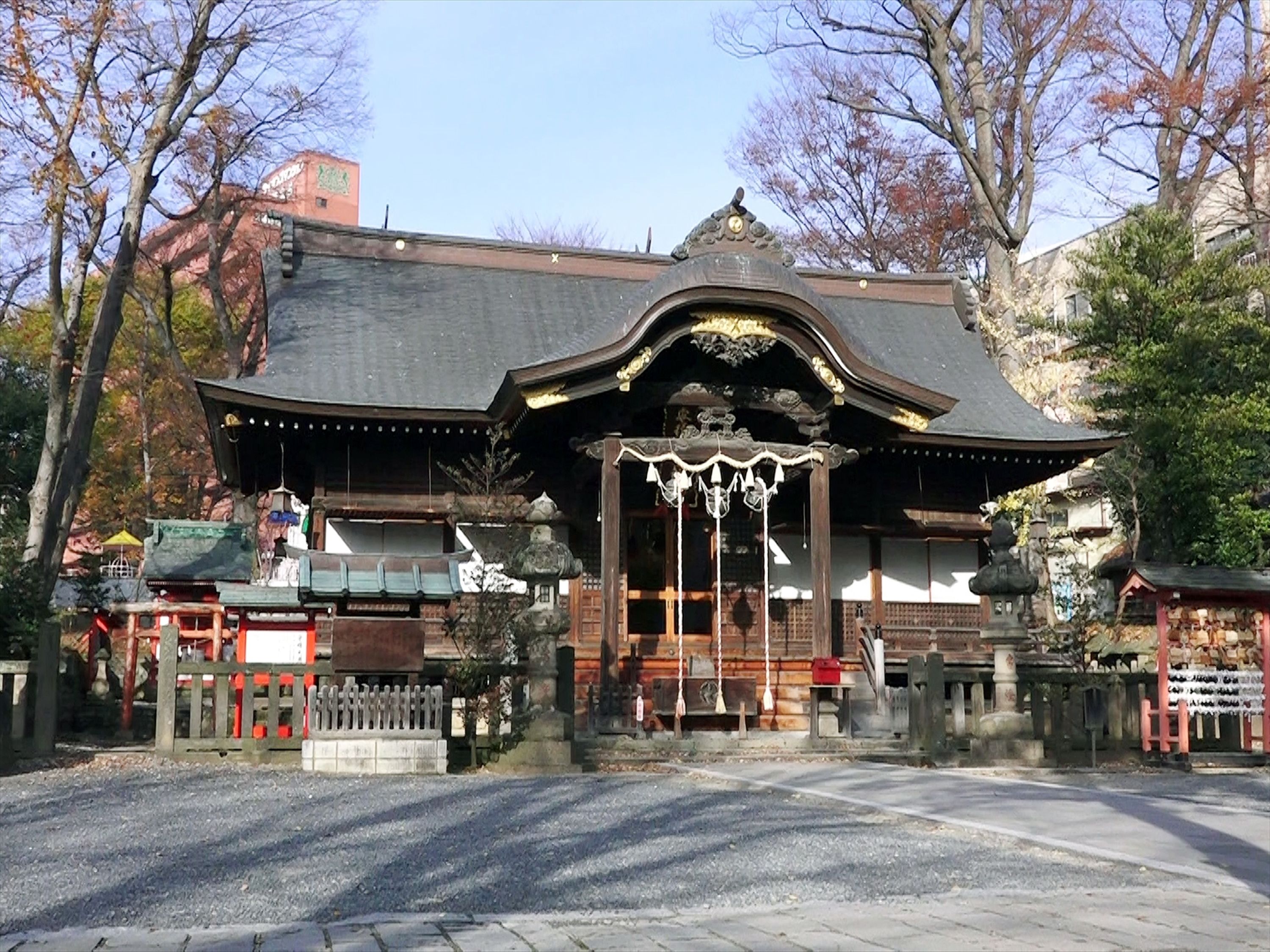 En traditionell japansk byggnad med ett tak täckt av tegelpannor, en träkonstruktion och en liten, tempelliknande entré.