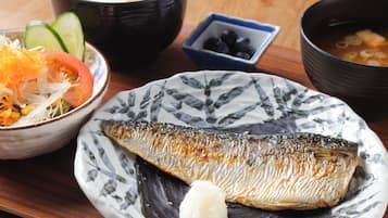 En måltid bestående av fisk, ris och grönsaker, serverad på ett träbord.