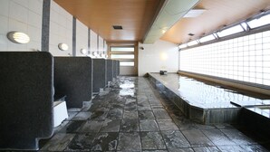 Een openbaar toilet met meerdere wastafels, betegelde muren en een houten plafond.