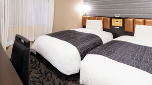 Een hotelkamer met twee bedden, een bureau en een bedieningspaneel aan de muur.