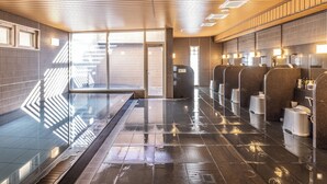 Ein modernes Badezimmer mit nassen Fliesen, einer Glasabtrennung und einer Holzzahl.