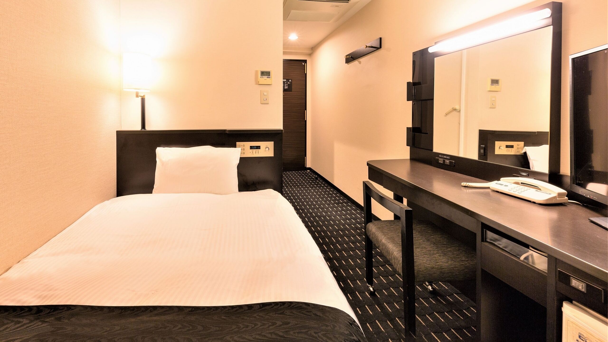 Ein Hotelzimmer mit Bett, Schreibtisch, Telefon und Spiegel.