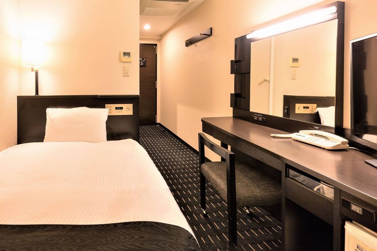 Ein Hotelzimmer mit Bett, Schreibtisch, Telefon und Spiegel.