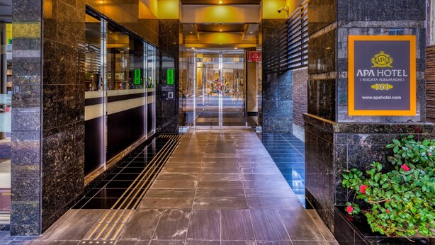 Eine Hotelhalle mit modernem Design, mit Marmorboden, einer Rezeption und einem Schild mit dem Hotelnamen und dem Ort.