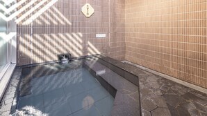Ein modernes Badezimmer mit Steinboden, einer eingebauten Badewanne und einer mit Fliesen verkleideten Wand mit einem Schild.