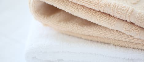 A folded beige towel on top of a white towel.