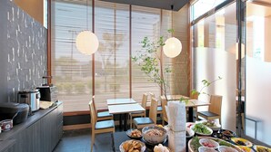 Un espace repas moderne avec une grande table dressée pour un repas, entourée de chaises en bois.