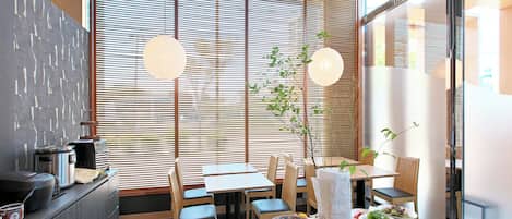 A modern dining area with a large table set for a meal, surrounded by wooden chairs.