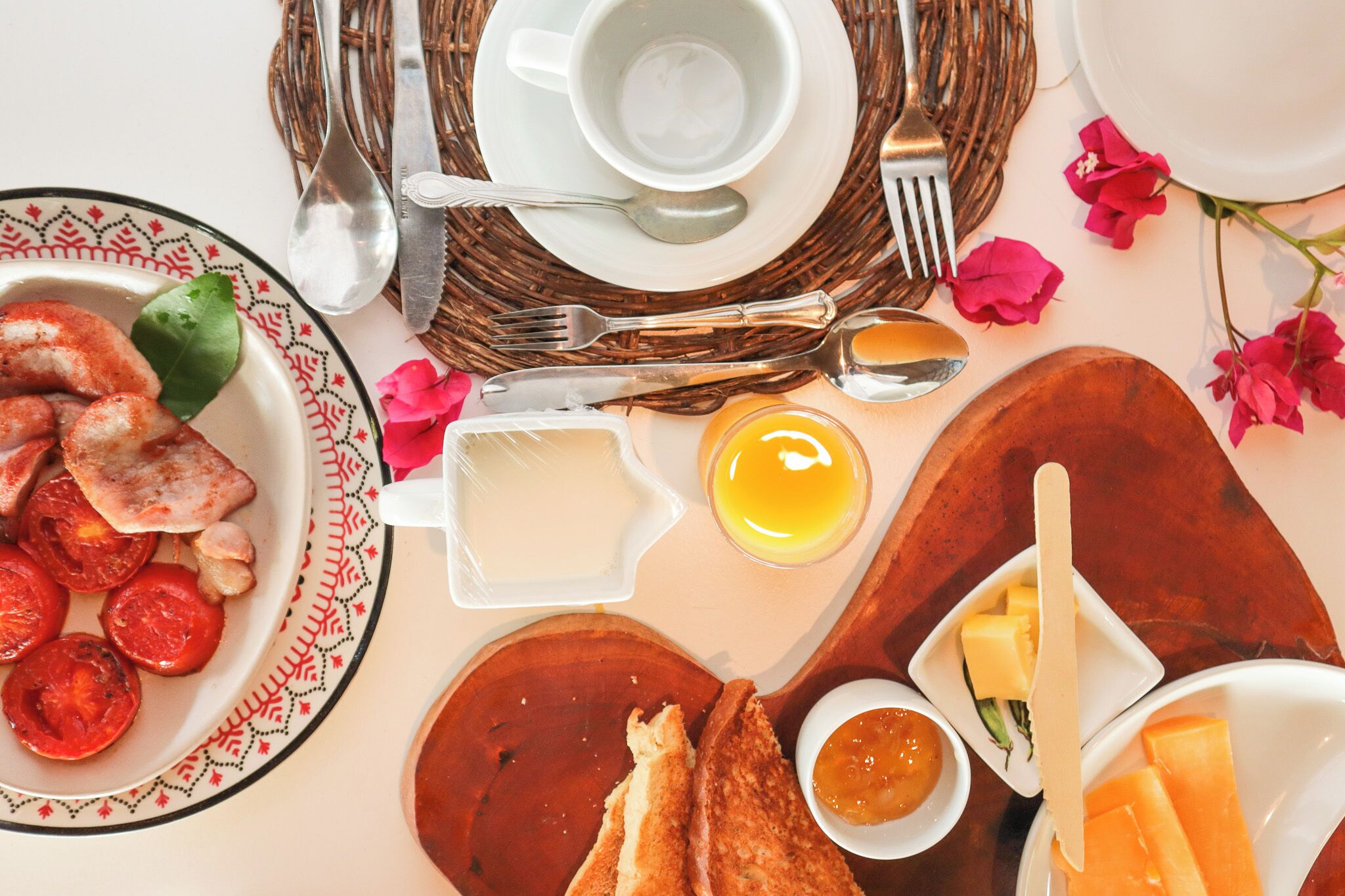 Une table mise pour le petit-déjeuner, avec des assiettes remplies de nourriture, des couverts et un set de table en fibres tressées.