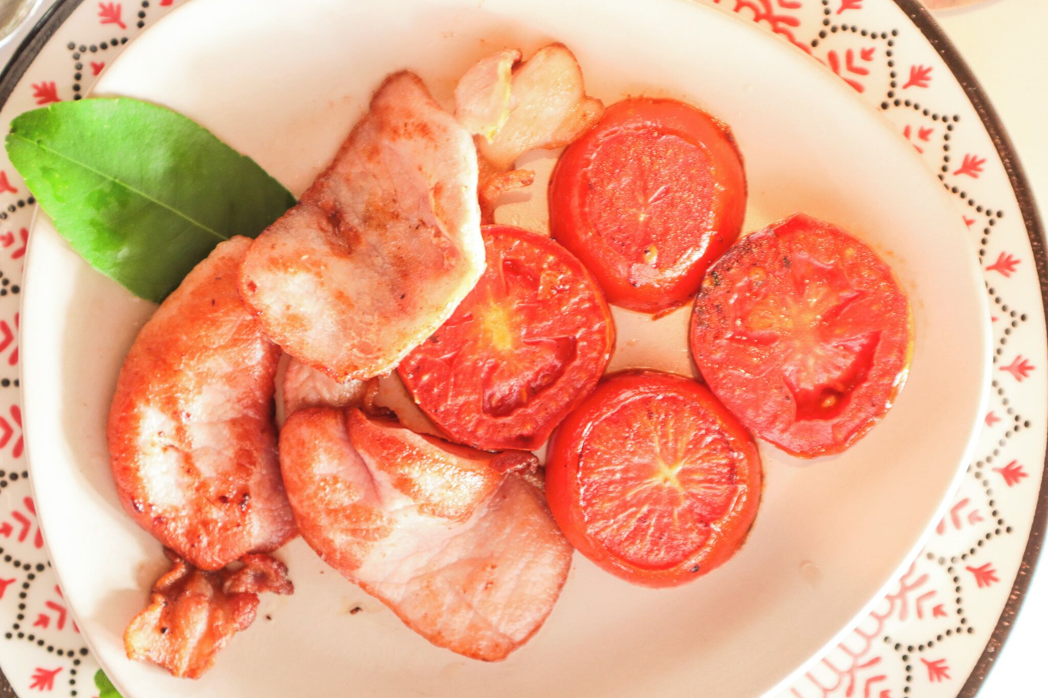 Une assiette avec des tomates coupées en tranches et une feuille de laurier.