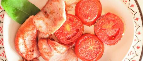 Une assiette avec des tomates coupées en tranches et une feuille de laurier.