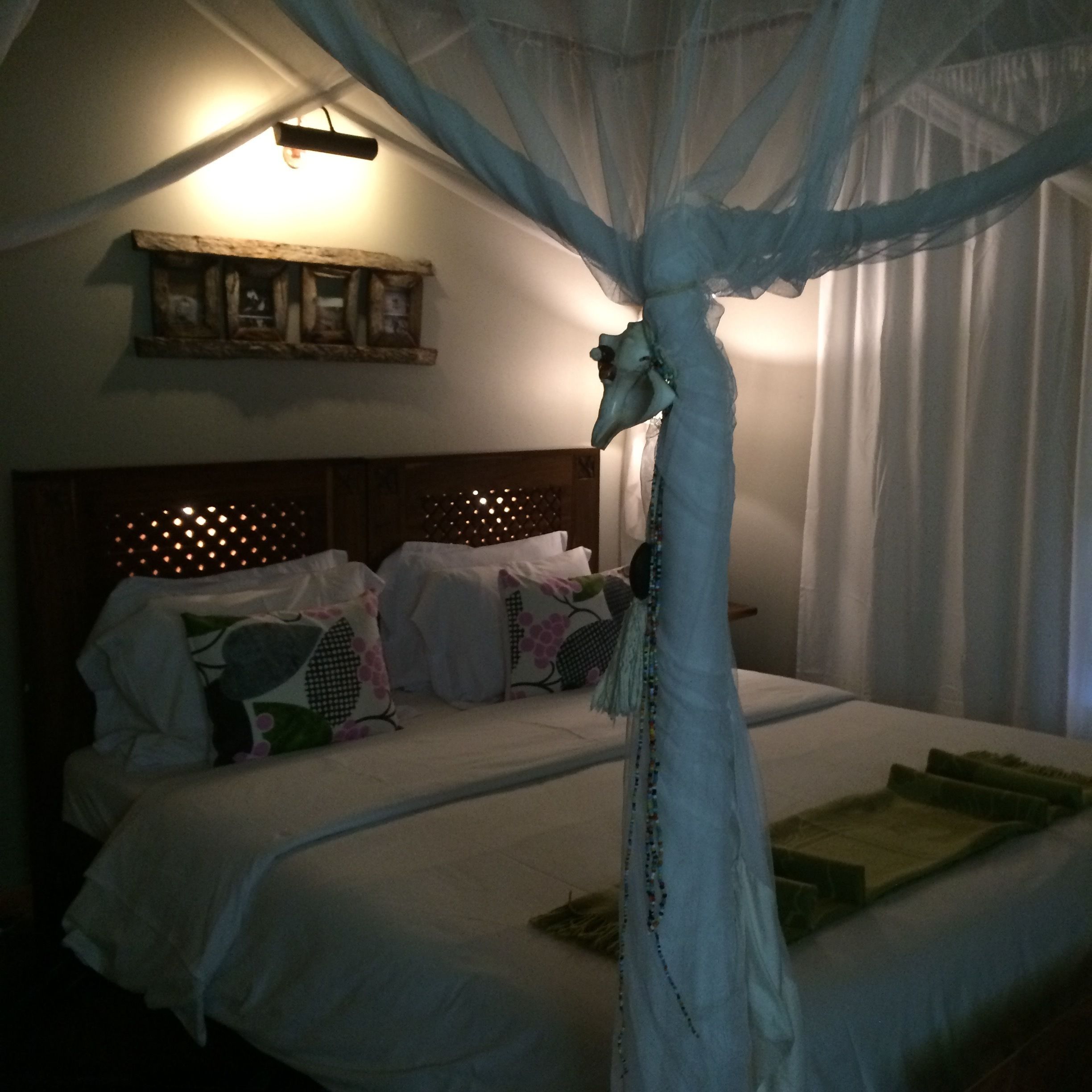 A bedroom with a canopy bed, a wooden headboard, and a wall-mounted light fixture.
