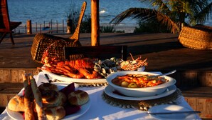 A table set with seafood, bread, and a bowl of soup, overlooking the ocean. - Villas do Indico Eco - Resort & Spa Lodge (Vilanculos)