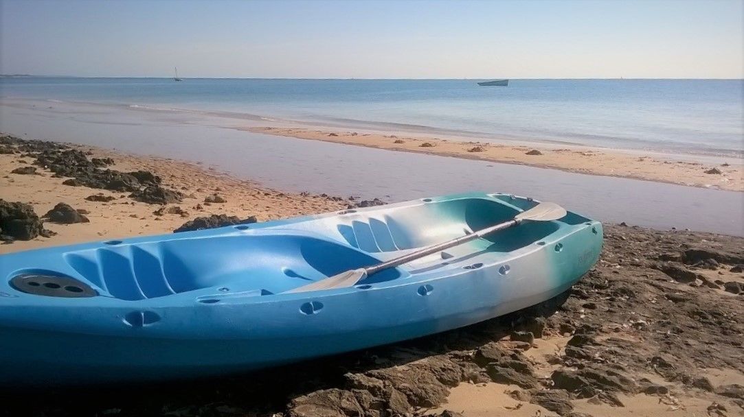 A blue inflatable boat on a rocky beach with a calm sea in the background.