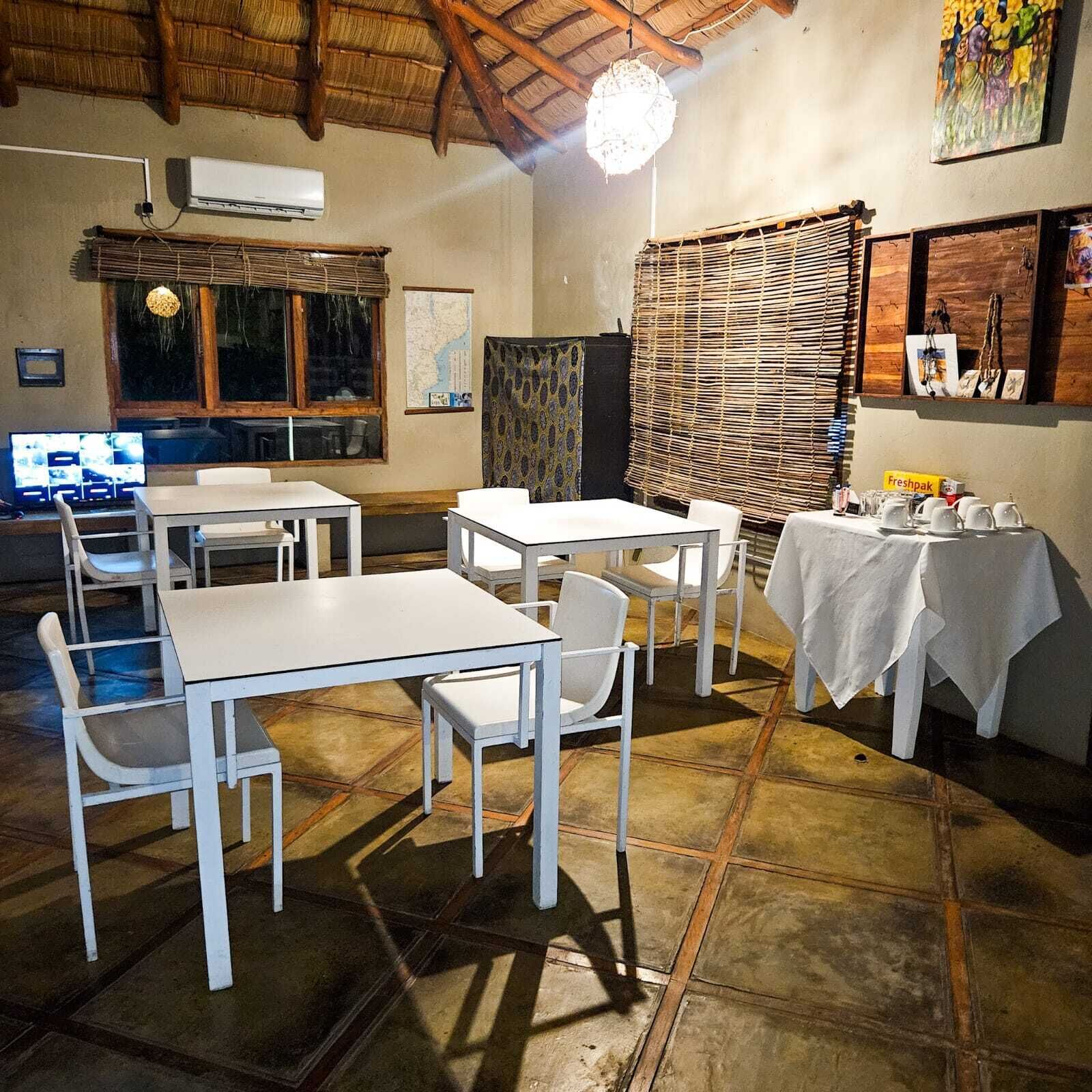 Un espace repas avec des tables et des chaises, un climatiseur fixé au mur, une carte et un panneau indiquant « Freshpak ».