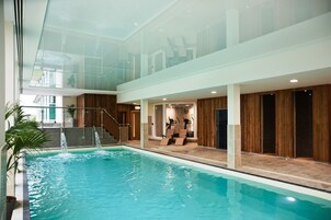 Una piscina interior con techo de vidrio, paredes de madera y equipo de ejercicios.