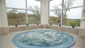A hot tub with a view of trees and a grassy area through large windows. - Best Western The Dartmouth Hotel Golf & Spa (Totnes)