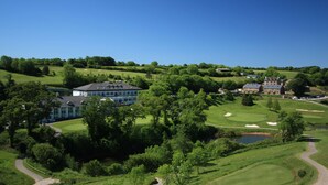 A golf course with a clubhouse, a pond, and surrounding greenery. - Best Western The Dartmouth Hotel Golf & Spa (Totnes)