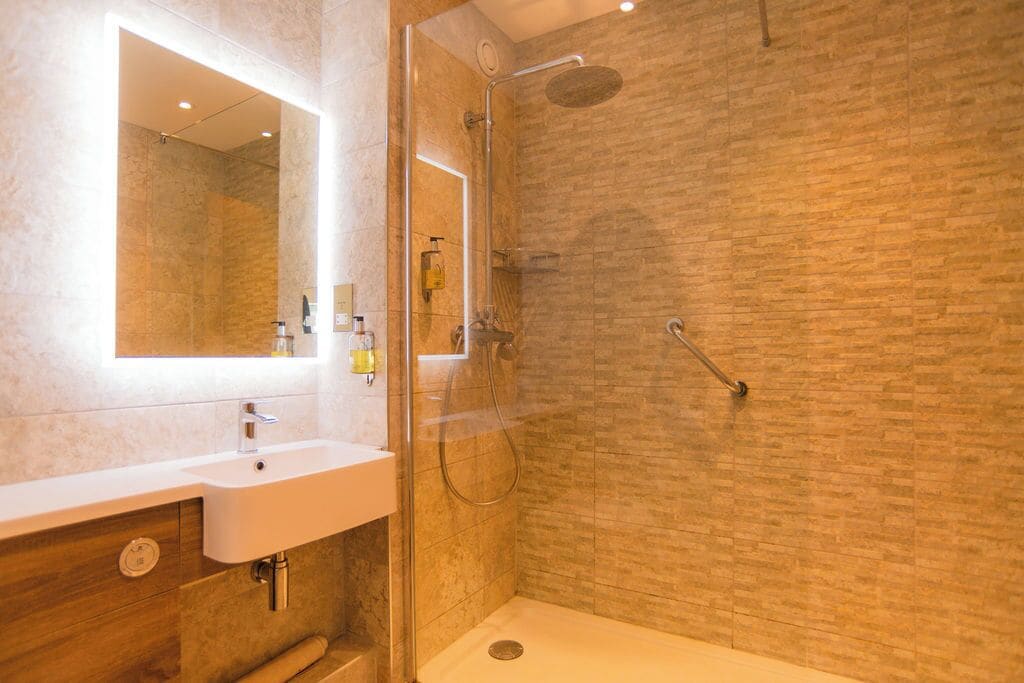 Un baño moderno con ducha de vidrio, un lavabo blanco y un espejo.
